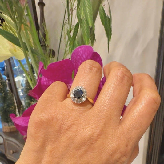 A sapphire and diamond circular cluster ring in yellow and white gold, modelled on a hand