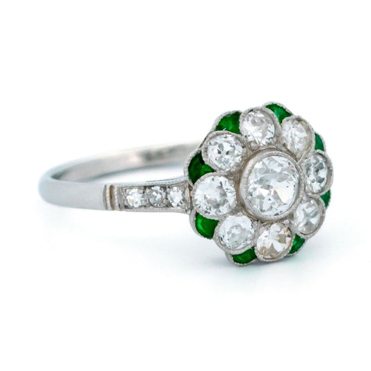 A diamond and emerald daisy cluster ring in platinum