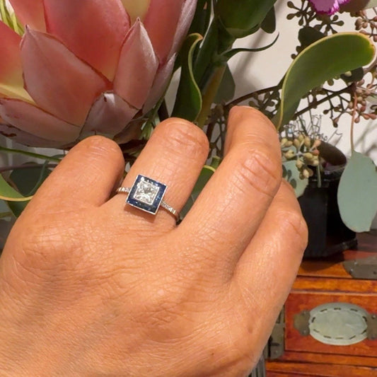 A square shaped cluster ring with diamonds and sapphires in platinum, modelled on a hand