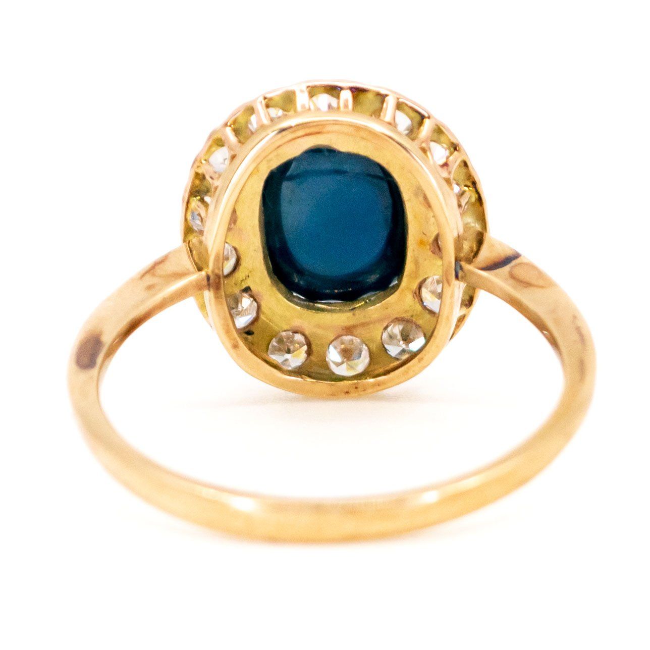 An oval cluster ring with a cabochon sapphire and diamond surround, in yellow gold