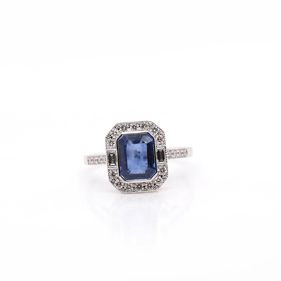 An emerald cut sapphire and diamond cluster ring in white gold