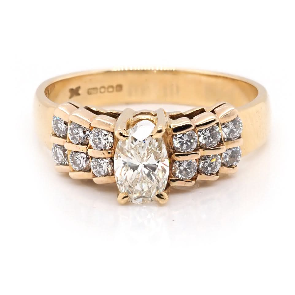 A yellow gold ring with a central oval cut diamond and brilliant cut diamond shoulders