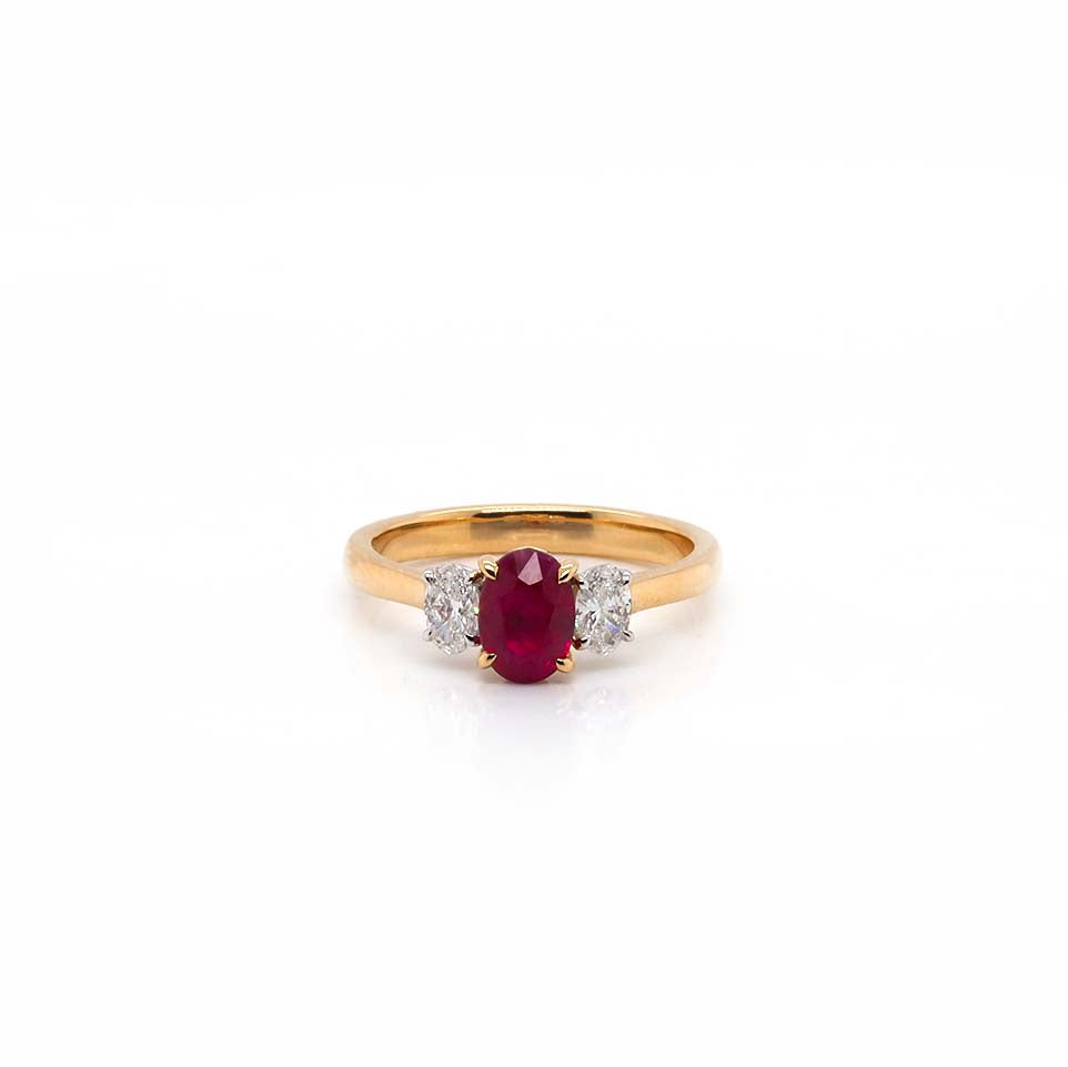 An oval ruby and oval diamond three stone ring in yellow and white gold