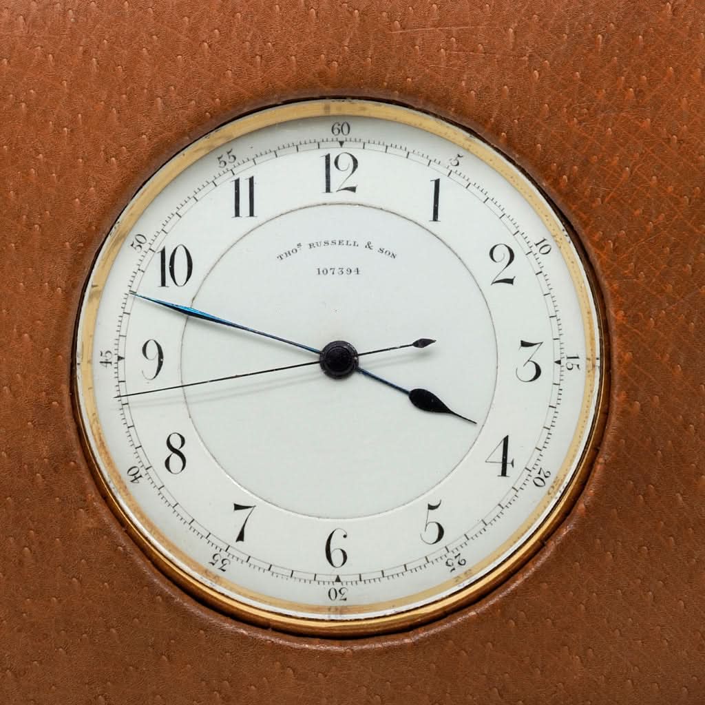 An antique open faced pocket watch by Thomas Russell in gold with a white dial, black Arabic numbers and hands, in a brown leather carrying case