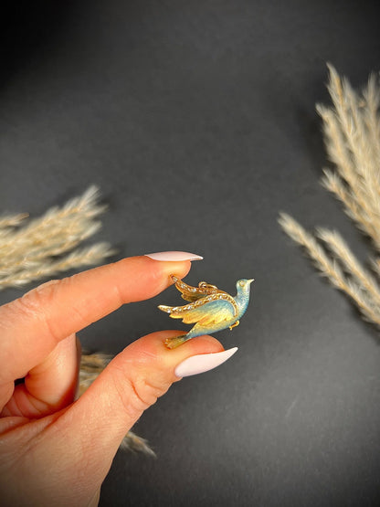 An enamel and diamond dove bird pendant, held in a hand