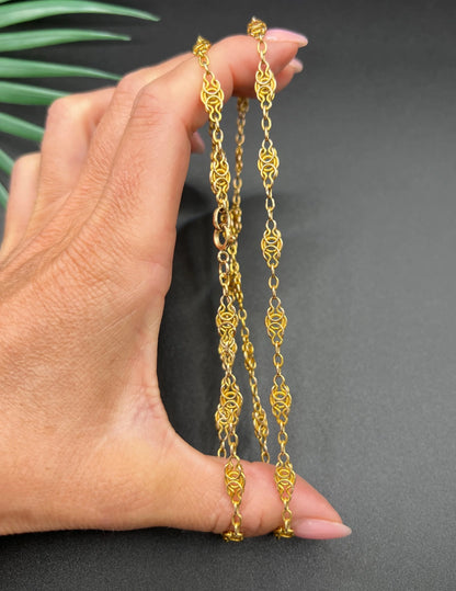 A yellow gold fancy link chain necklace, held in a hand