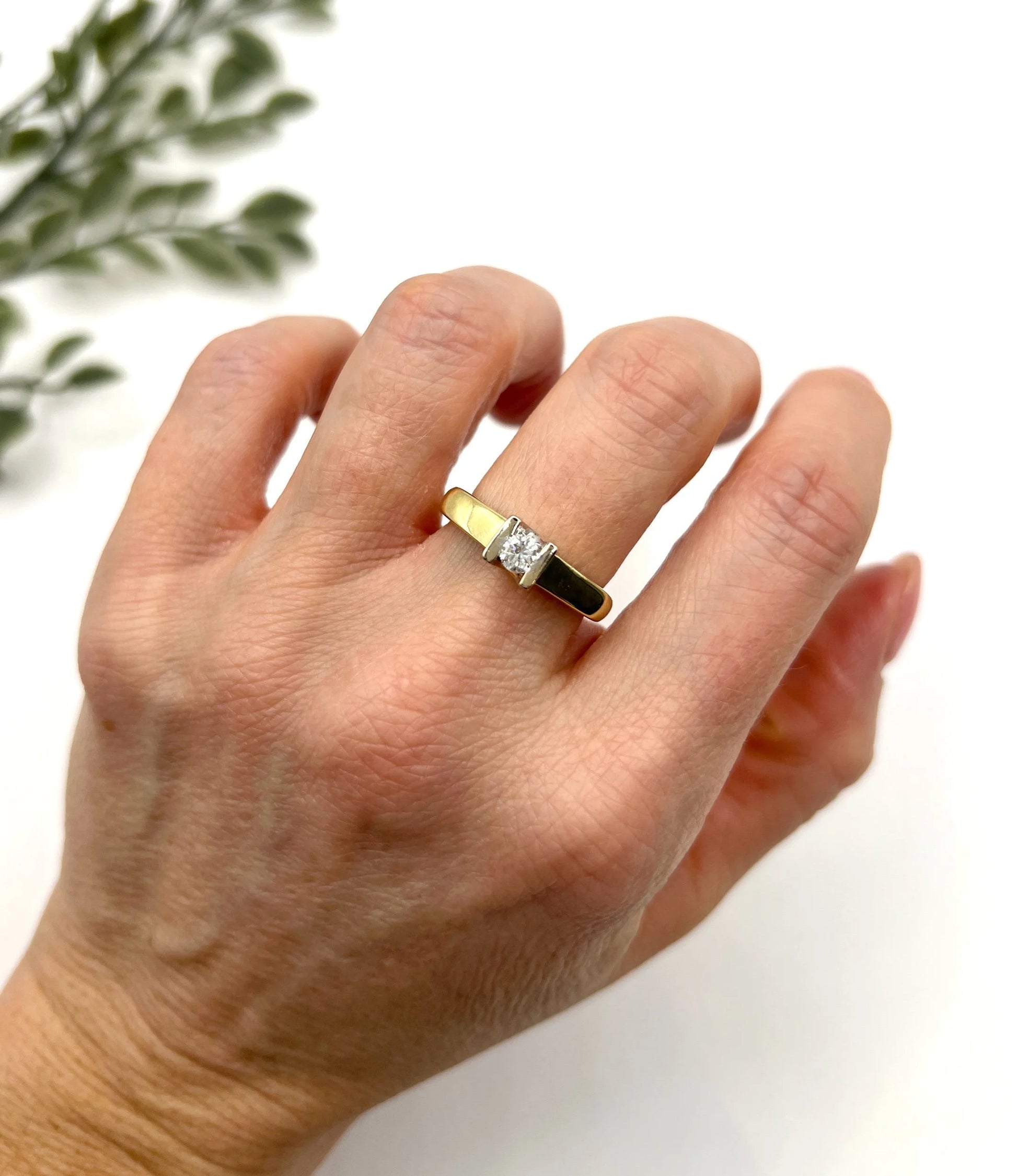 A brilliant cut diamond solitaire ring in yellow gold, modelled on a hand