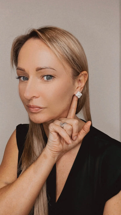 A diamond cluster stud earring, modelled by a woman wearing a black top