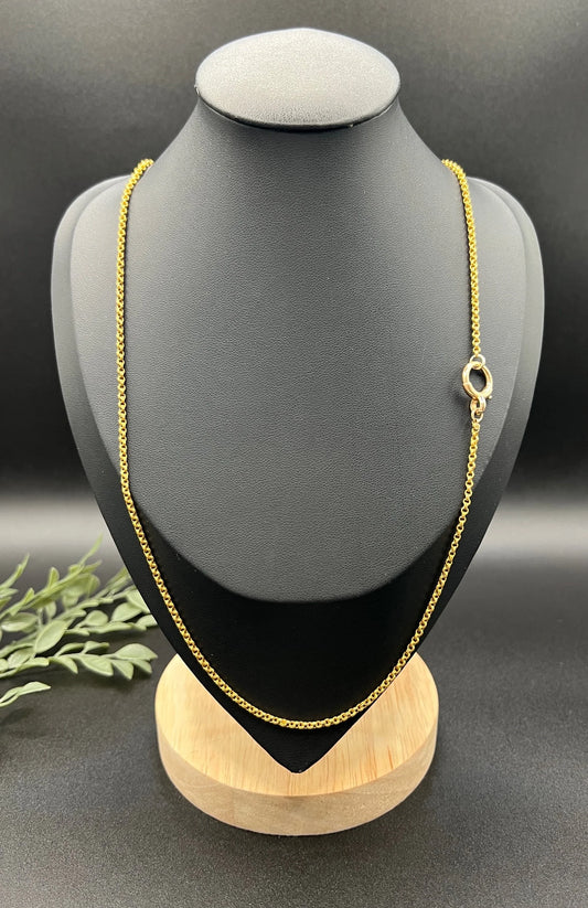 A yellow gold rolo link chain necklace, on a black jewellery bust