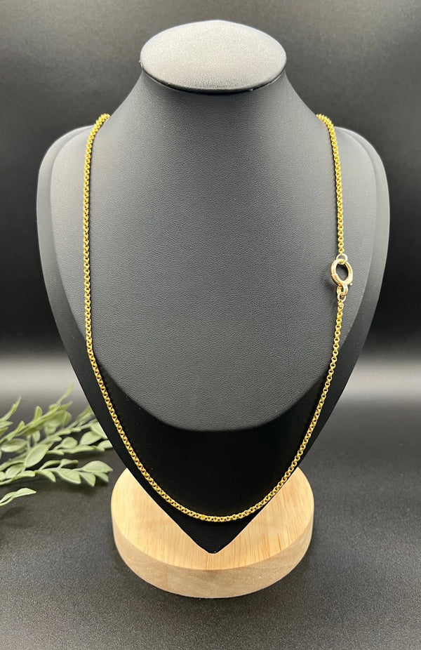 A yellow gold rolo link chain necklace, on a black jewellery bust