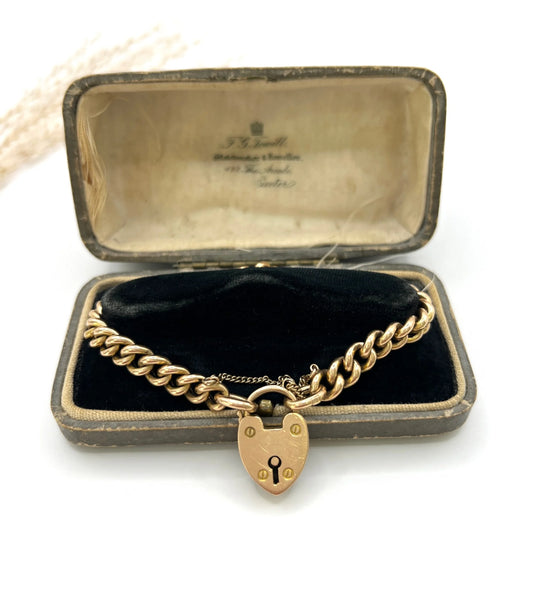 A gold curb link bracelet with heart shaped padlock, in an antique box