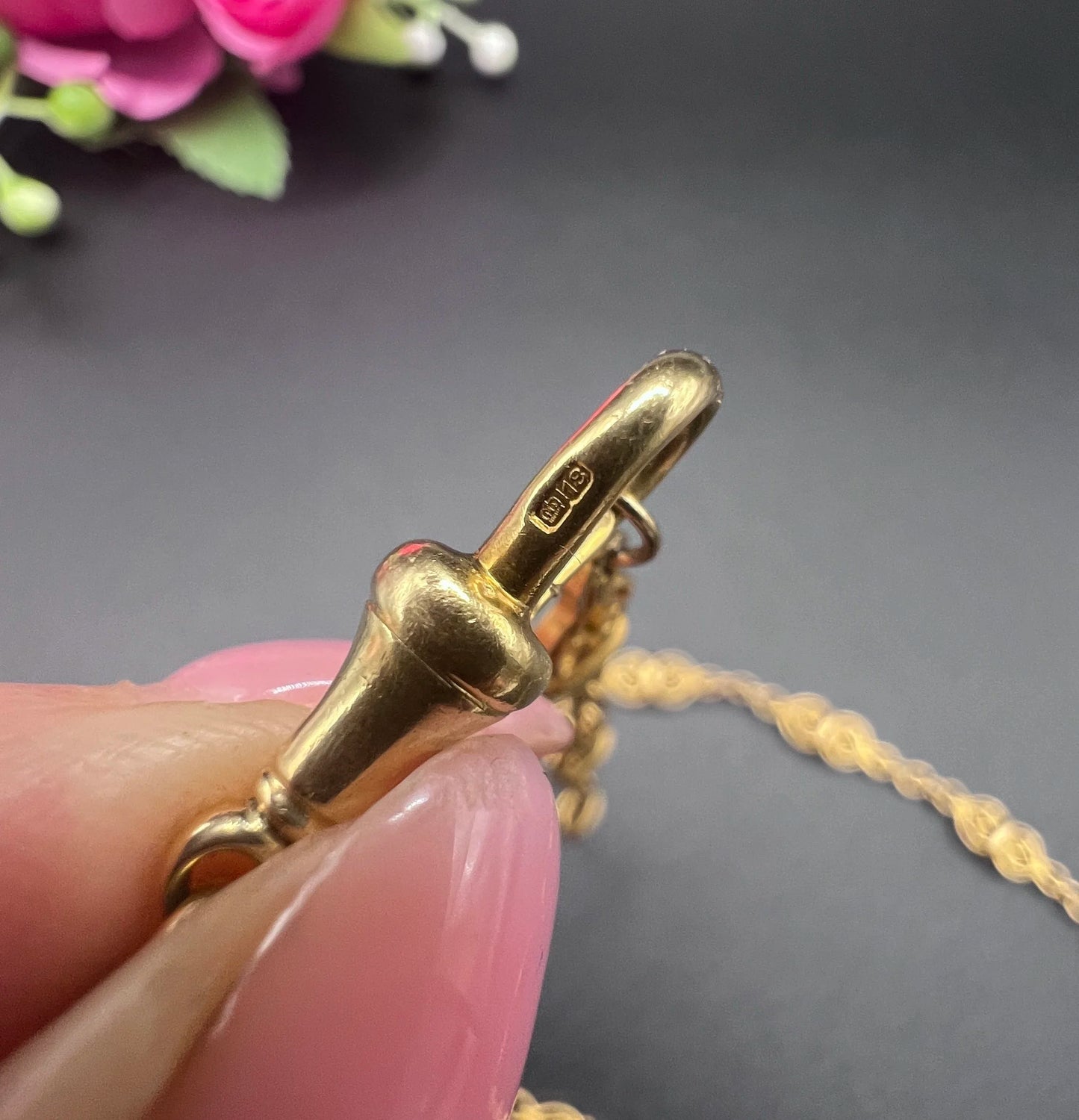 Close-up of stamps on a yellow gold necklace clasp