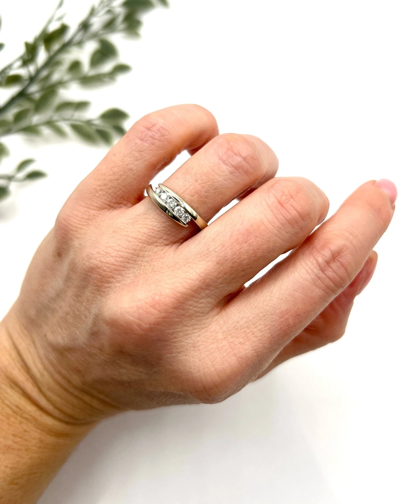 A five stone brilliant cut diamond ring in white gold, modelled on a hand