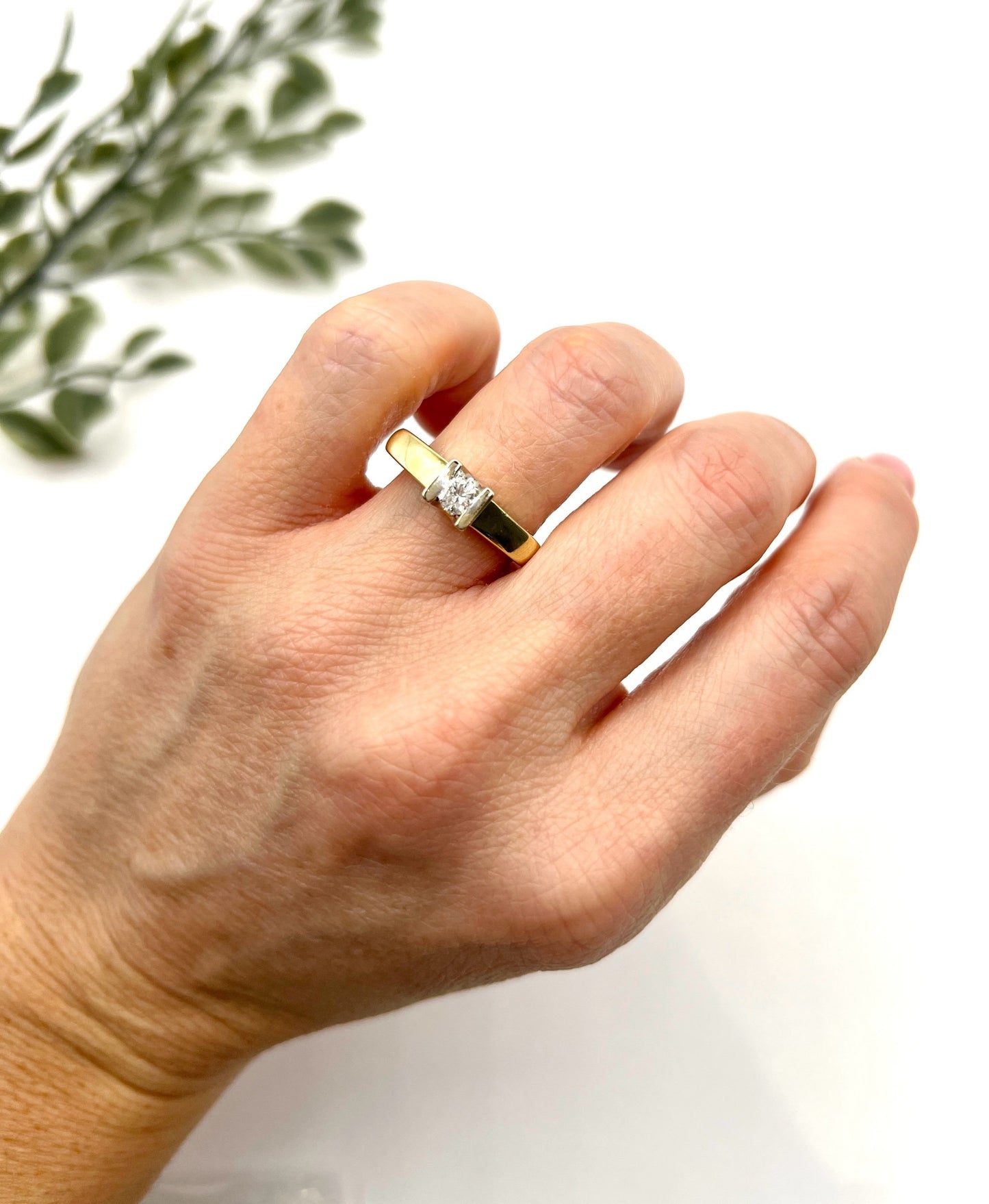 A brilliant cut diamond solitaire ring in yellow gold, modelled on a hand