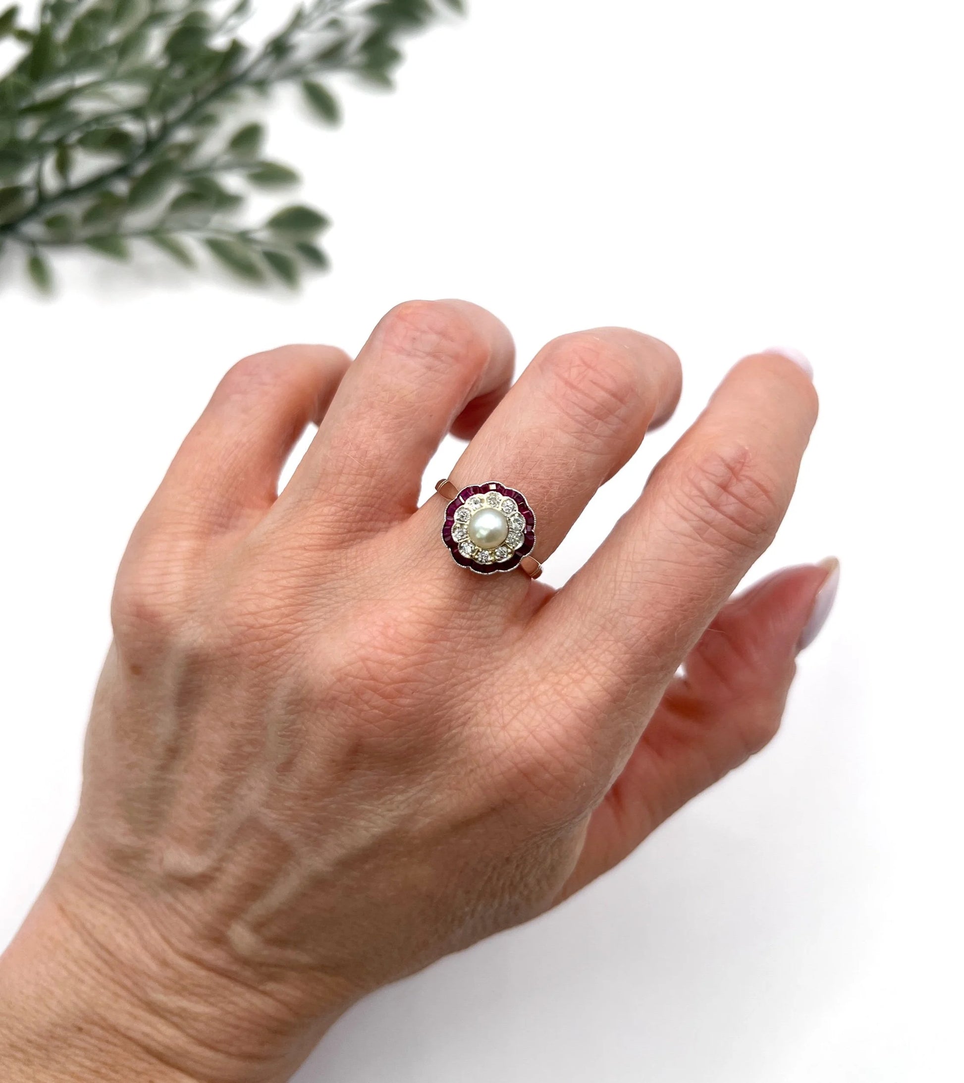 A pearl, diamond and ruby fancy cluster ring in platinum and yellow gold, modelled on a hand