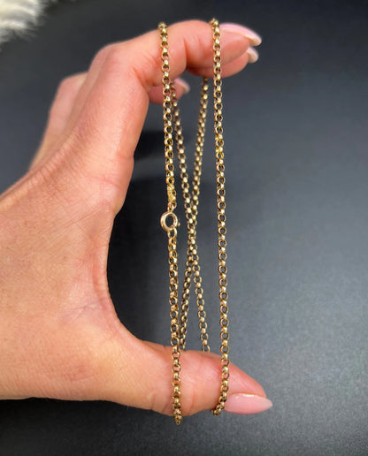 A gold belcher link necklace, held in a hand