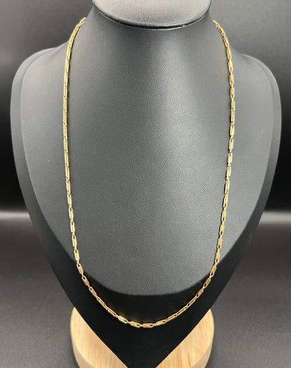 A gold paperclip link chain necklace, on a black bust