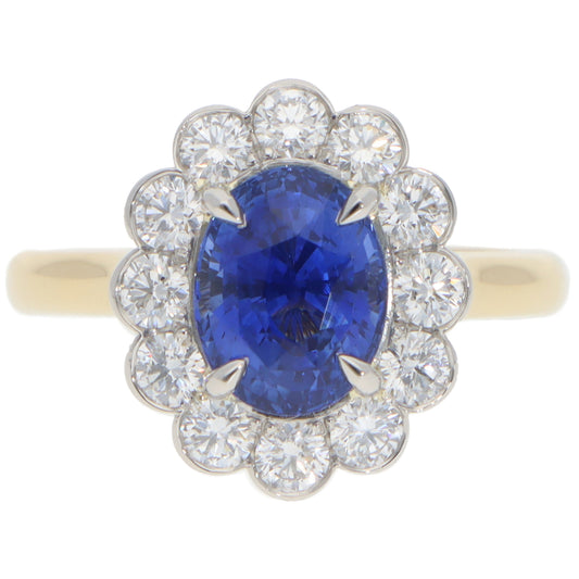 An oval sapphire and round diamond cluster ring in yellow gold and platinum, on a white background