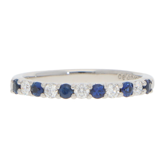 A half eternity band with sapphires and diamonds in platinum, on a white background