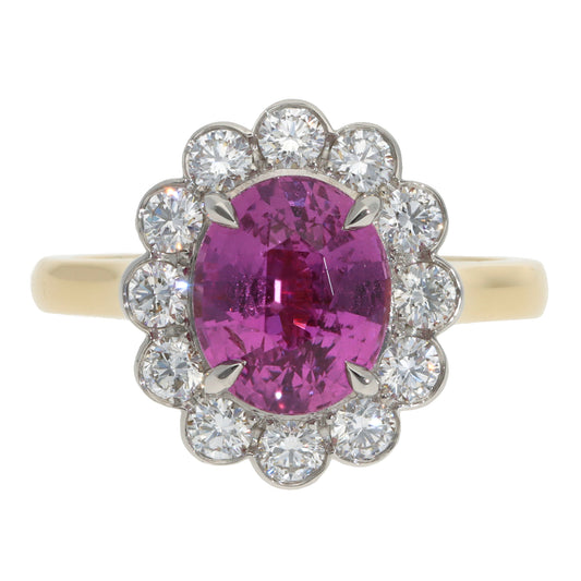 A pink sapphire and diamond oval cluster ring in yellow gold and platinum, on a white background