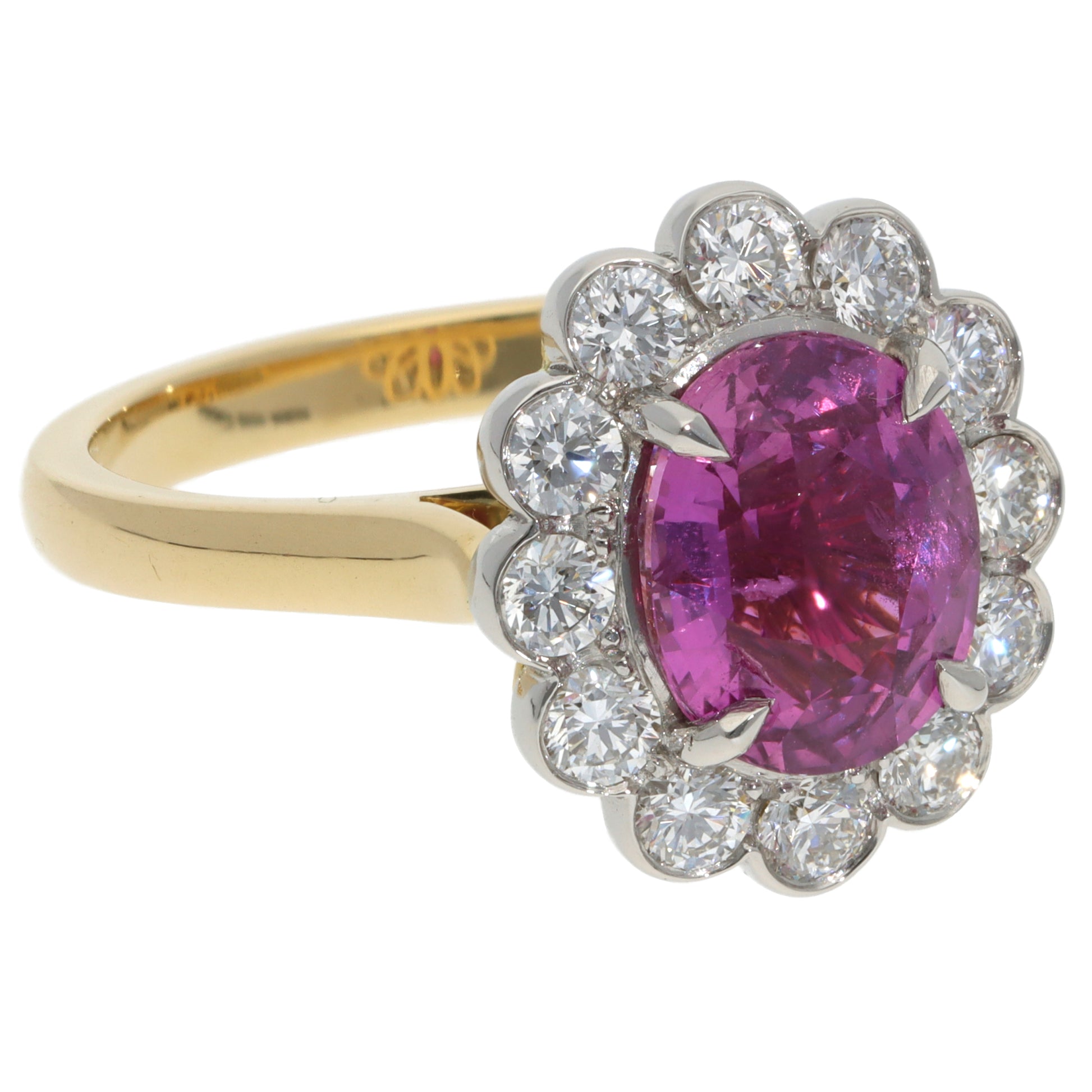 A pink sapphire and diamond oval cluster ring in yellow gold and platinum, on a white background