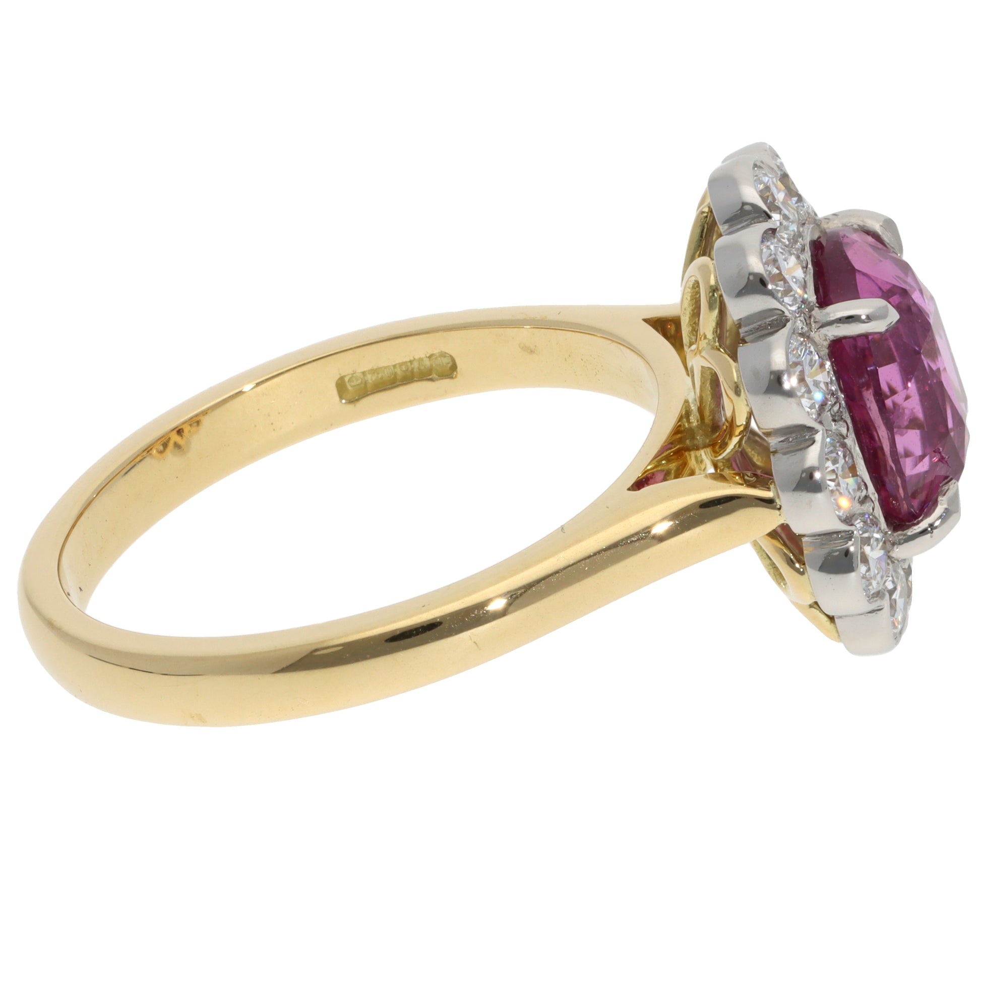 A pink sapphire and diamond oval cluster ring in yellow gold and platinum, on a white background