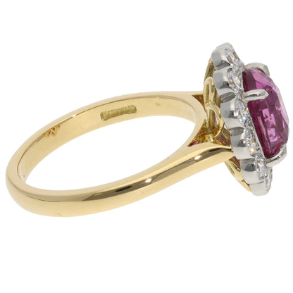 A pink sapphire and diamond oval cluster ring in yellow gold and platinum, on a white background