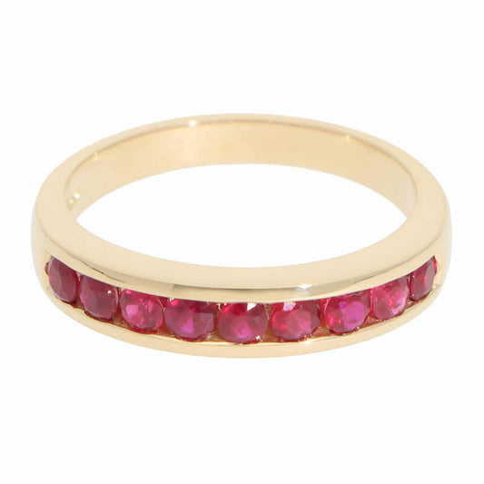 A yellow gold half eternity band with round rubies, on a white background