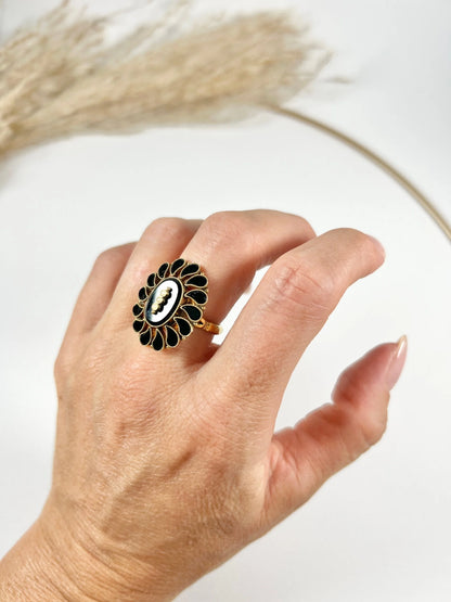 A black onyx and seed pearl fancy halo cluster ring in yellow gold, modelled on a hand