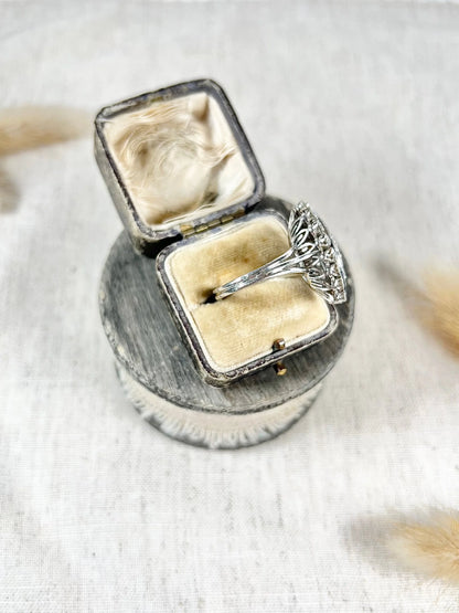 A navette shaped diamond cluster ring in white metal, in an antique ring box