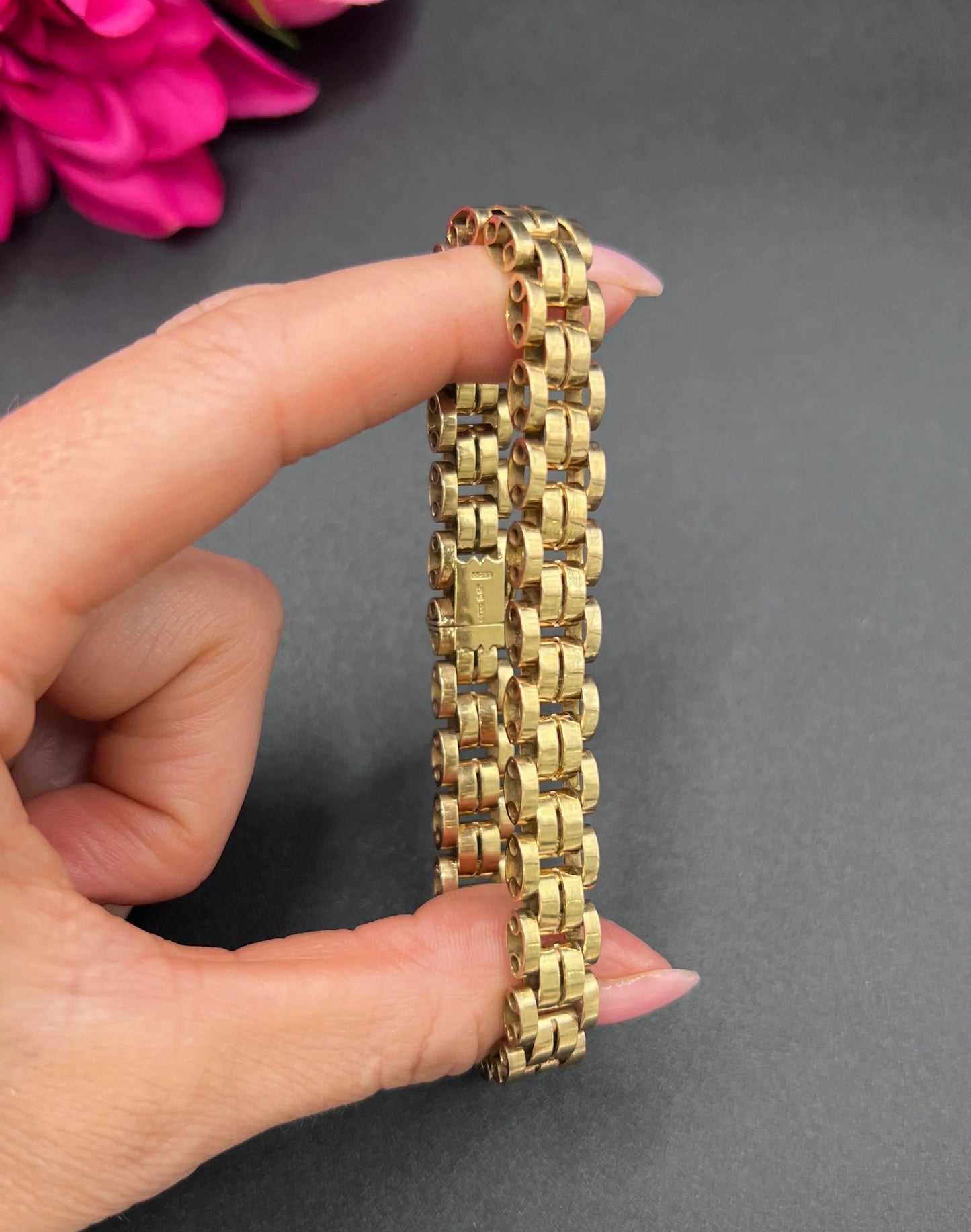 A yellow gold link bracelet, held in a hand