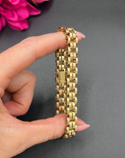 A yellow gold link bracelet, held in a hand