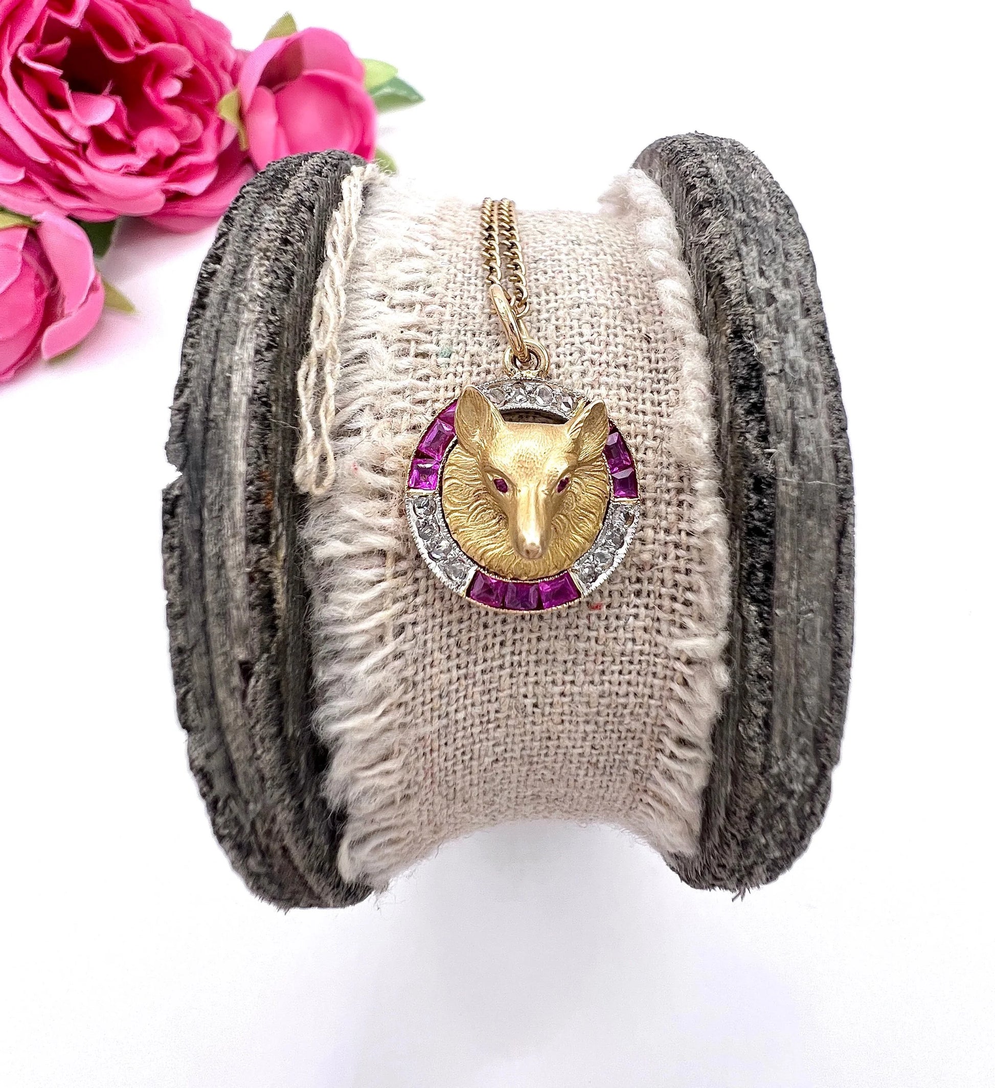 A fox head pendant in yellow gold with a ruby and diamond border, with a gold chain