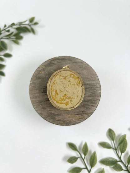 An oval cherub lava cameo pendant in yellow gold