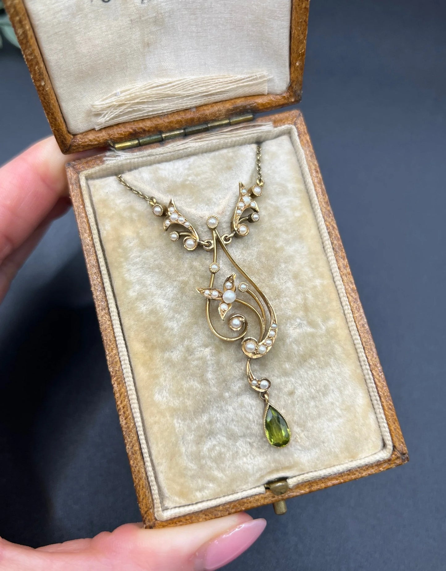A yellow gold floral pendant necklace with pearls and a peridot drop, in an antique box