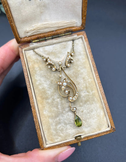A yellow gold floral pendant necklace with pearls and a peridot drop, in an antique box