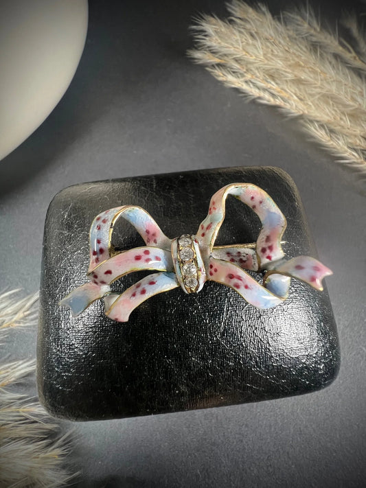 A blue and pink enamel bow brooch with diamonds in yellow gold
