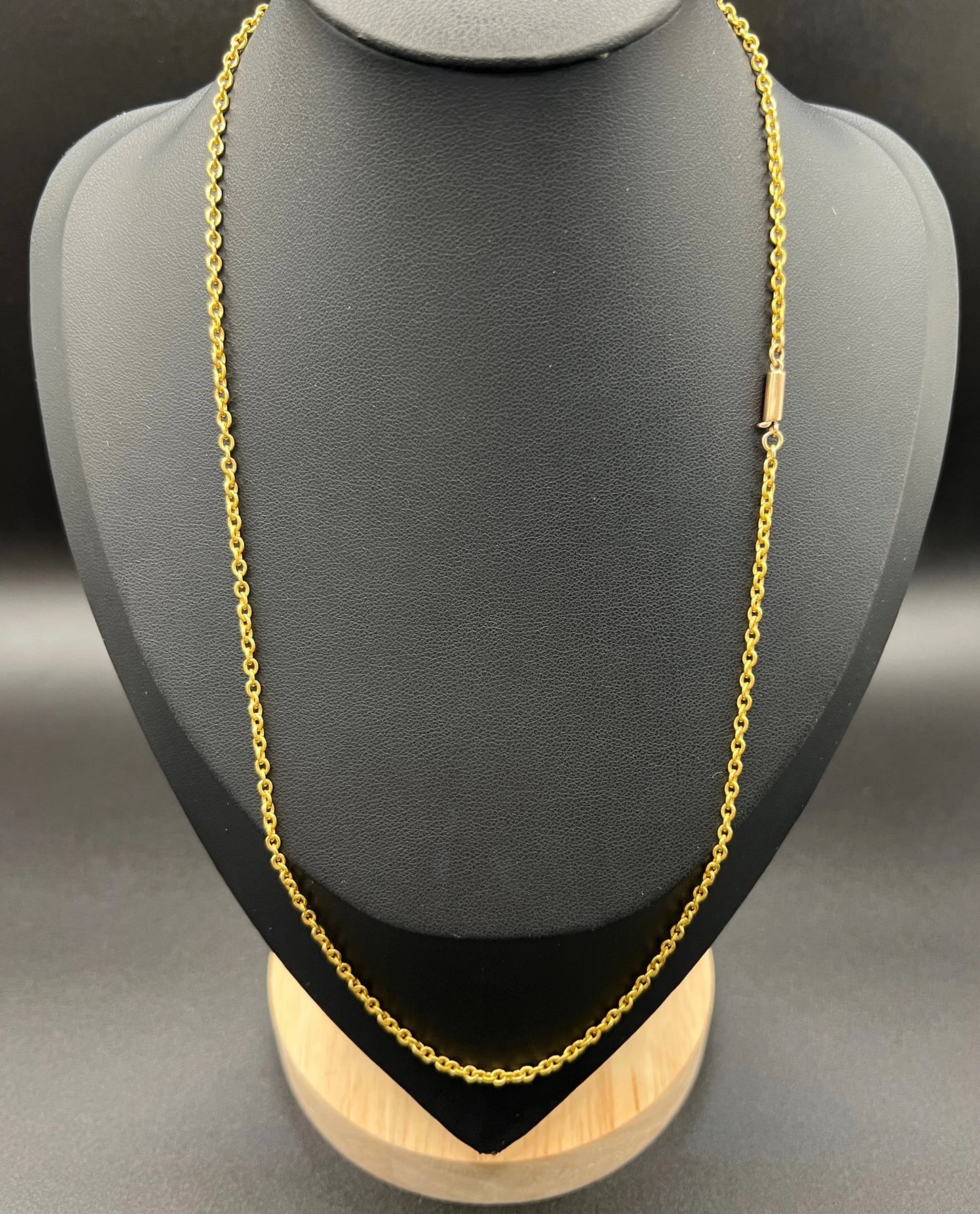 A yellow gold trace link chain necklace, modelled on a black jewellery bust
