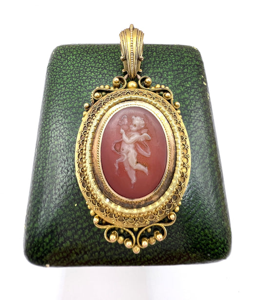 An ornate yellow gold oval cherub cameo locket pendant, on an antique box