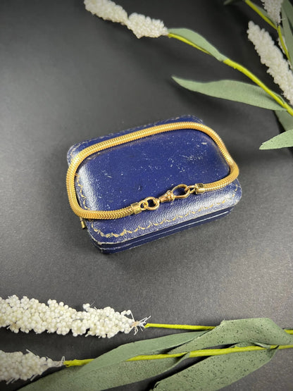 A yellow gold snake link bracelet, laid on a blue antique box