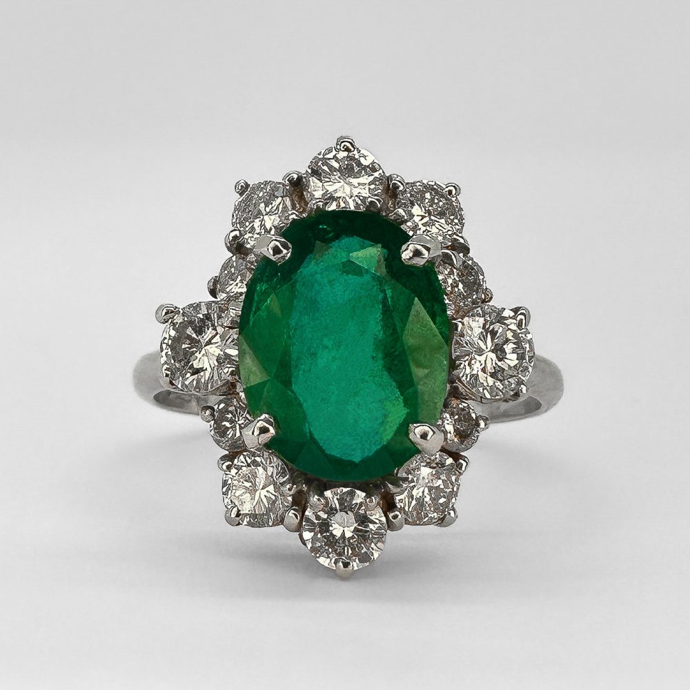 Vintage oval cut emerald and diamond cluster engagement ring in 18ct white gold