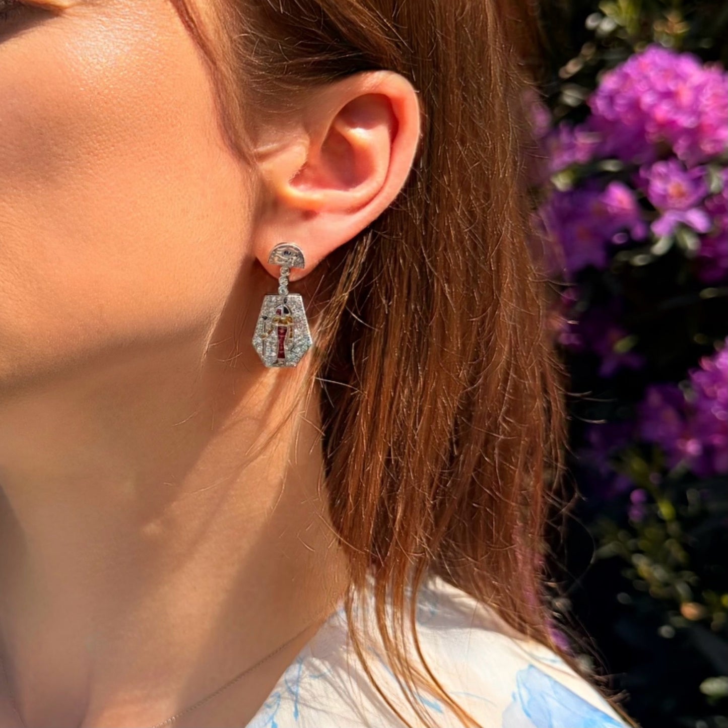 An Eye of Horus drop earring set with diamonds, rubies, emeralds, blue sapphires and yellow sapphires, in platinum, modelled in an ear