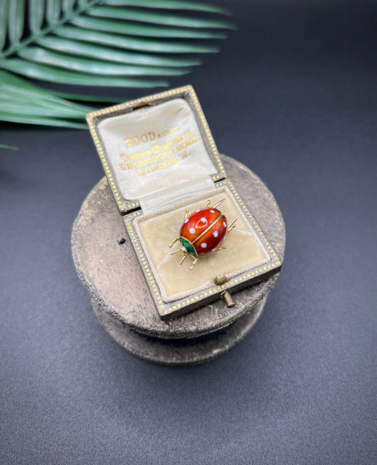A yellow gold and enamel ladybird brooch, in an antique box
