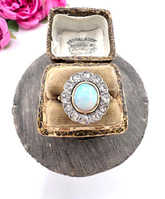 An oval opal and diamond cluster ring in yellow and white metal, in an antique ring box