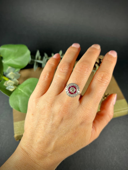 A round cluster ring with rubies and diamonds in white gold, modelled on a hand