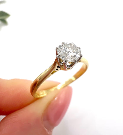 A single stone brilliant cut diamond ring claw set in platinum and yellow gold, held in a hand