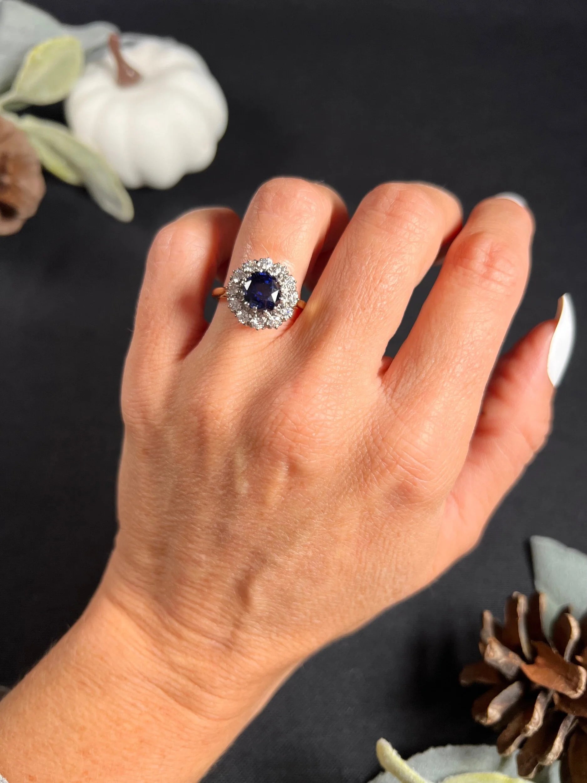 A round sapphire and diamond cluster ring, modelled on a hand