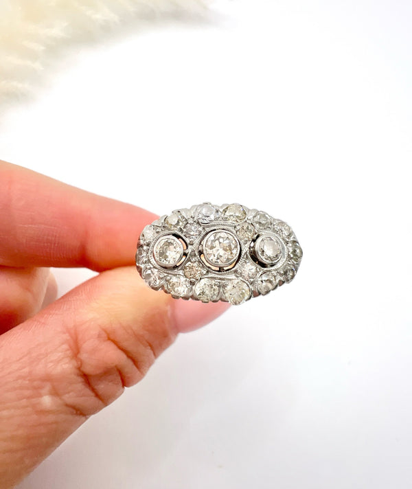 A diamond triple cluster ring in yellow and white gold, held in a hand