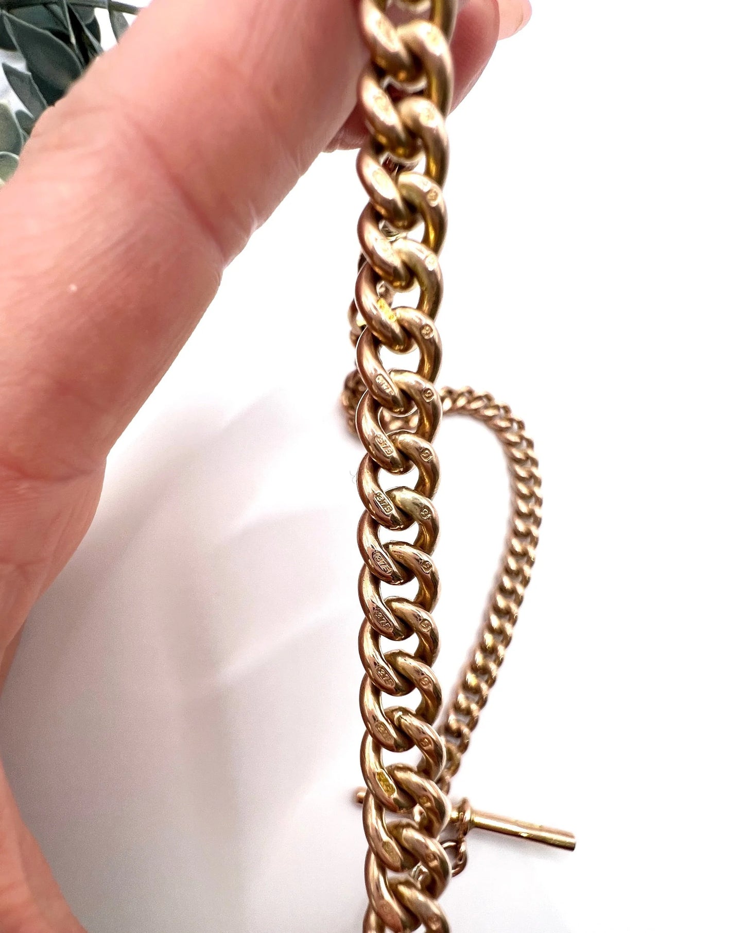 Close-up of rose gold curb links held in a hand