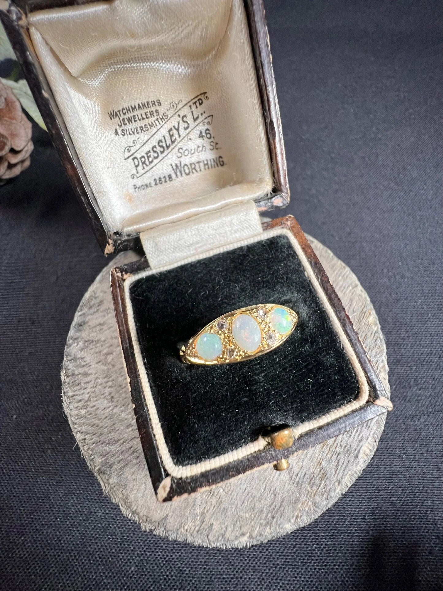 A boat-shaped gold ring with opals and diamonds, in a ring box
